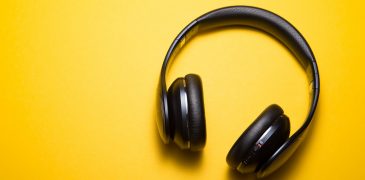 Black headphones laying on yellow backdrop