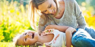 woman and daughter laughing in field
