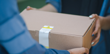 Delivery person handing off cardboard box to customer